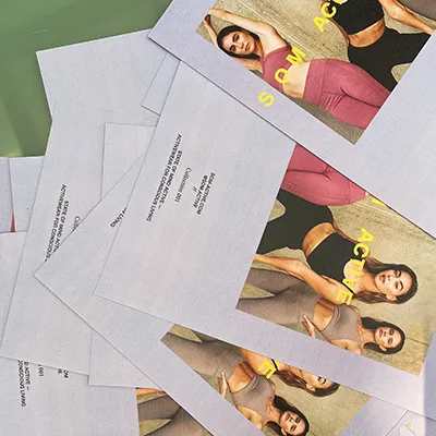 Scattered printed flyers featuring three models in SOM Active sets, with the brand name in yellow