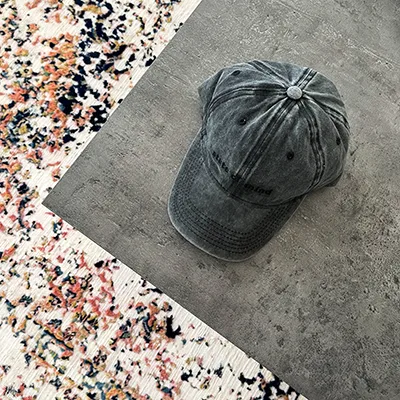 Washed grey SOM Active cap photographed on a concrete tile beside a patterned rug